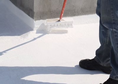 worker spreading silicone roofing material